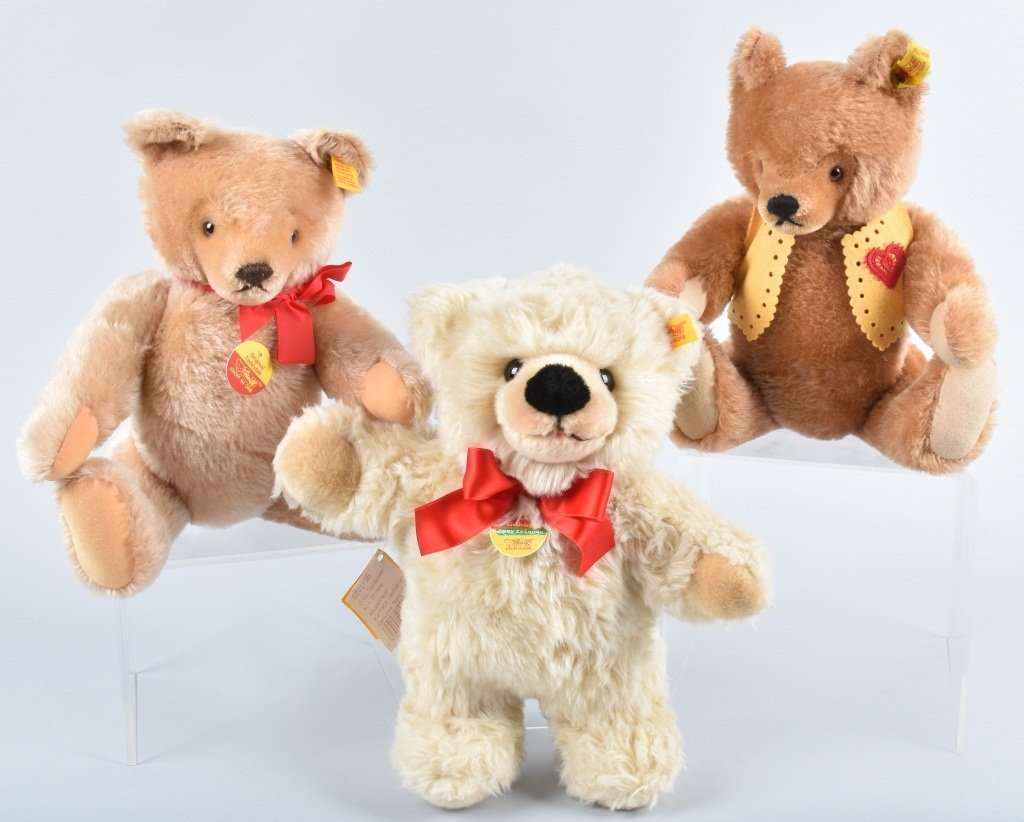 STEIFF BEARS GROUP OF 3: 1)Steiff Bobby Teddy Bear. He was made in 2004/2005 he is 11 inches and is made of champagne woven fur. So soft and cuddly. He has a yellow flag EAN 021817and his Bobby tag along with his red bow. His