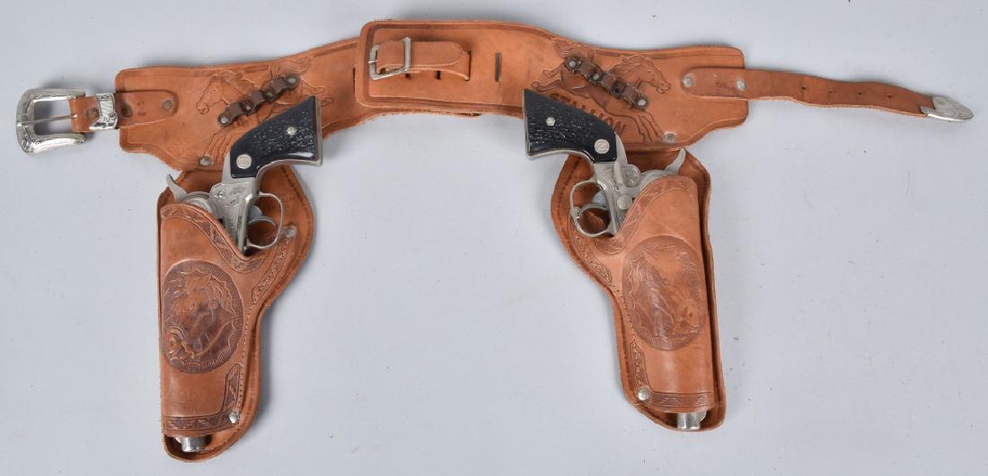 NICHOLS STALLION 38 DOUBLE HOLSTER CAP GUN SET: Set includes 2 working Nichols Stallion 38 cap guns, along with matching tooled leather belt and holsters. Guns are nice nice and should clean to a higher grade. Light wear. Very Good-Excellent