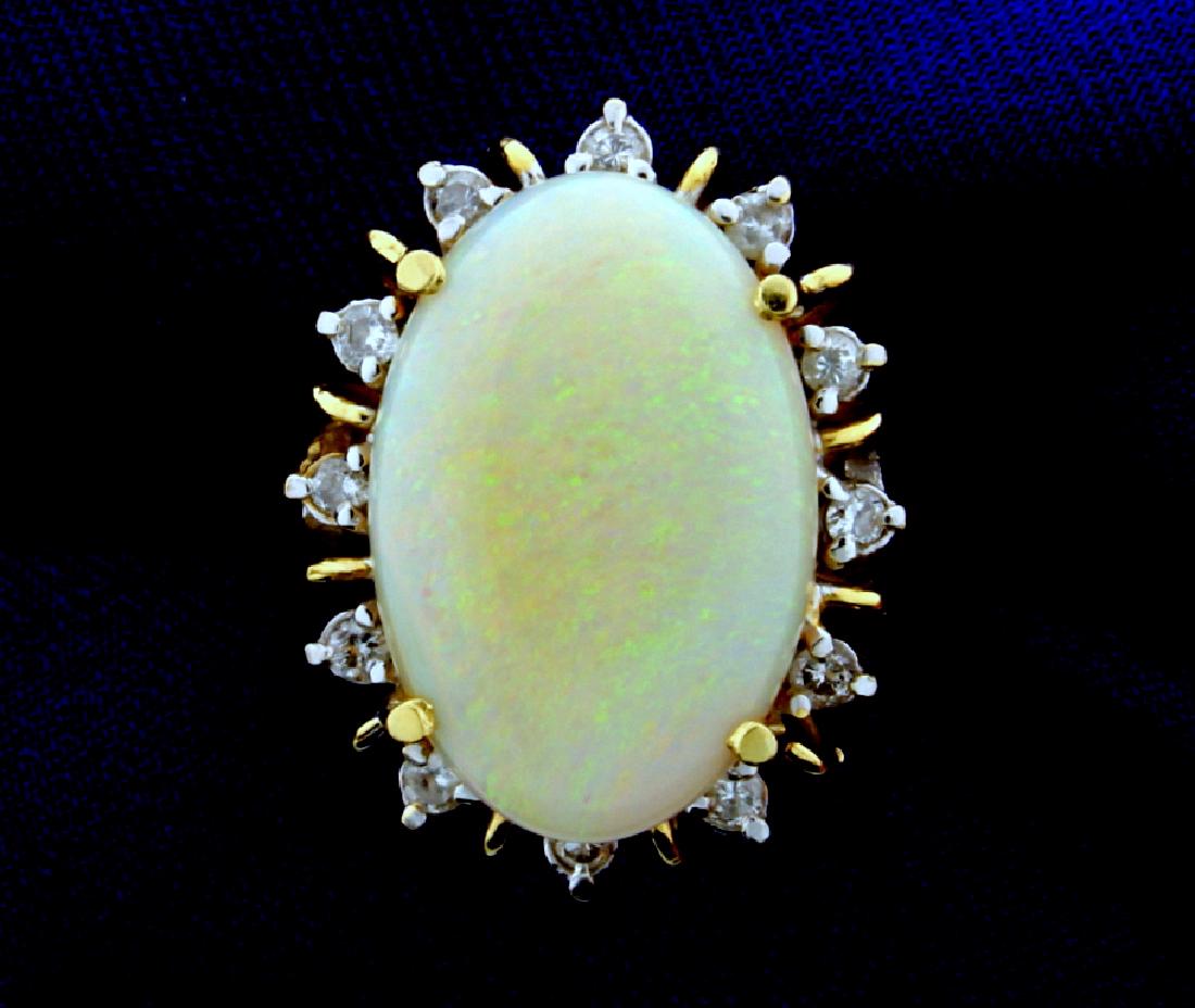Large Opal & Diamond Ring: In 14K yellow gold. The center is a 20x13mm oval opal with excellent play of color. Surrounded by twelve .03ct round diamonds, for a total weight of .36cts. Size 7, this ring has stabilizing balls 7.9