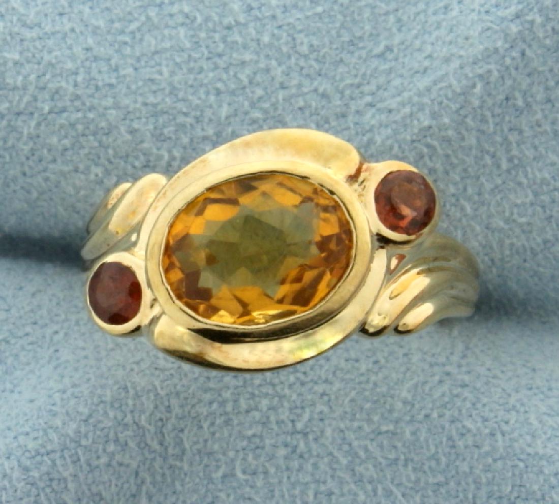 Citrine and Garnet Ring: In 10k yellow gold. Center stone is a 2.5ct natural citrine with excellent yellow orange color and excellent clarity. Also contains two .1ct natural garnet gemstones with excellent color and clarity. 