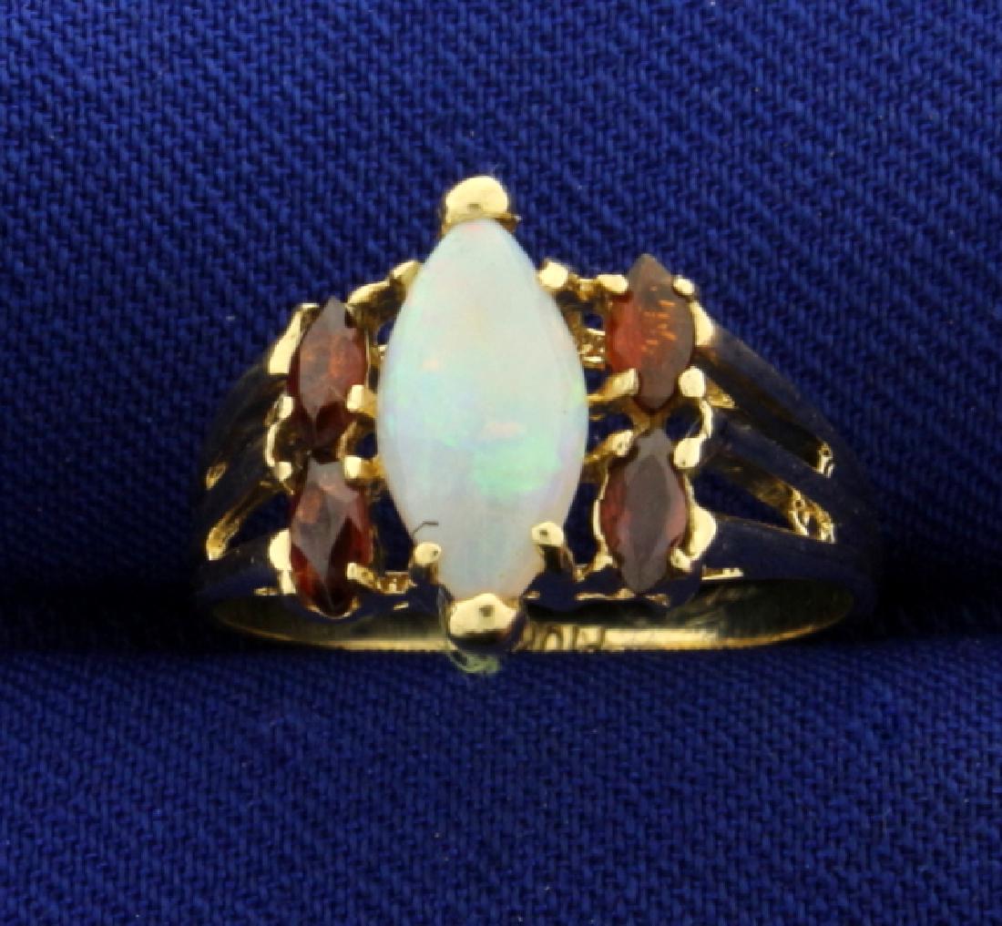 Natural Opal and Garnet Gemstone Ring: In 10k yellow gold. Contains a natural 10x5mm opal gemstone with flashes of green and orange. Also contains four natural 4x2mm garnet gemstones with deep red color and excellent clarity. Size 6. 2.3g.