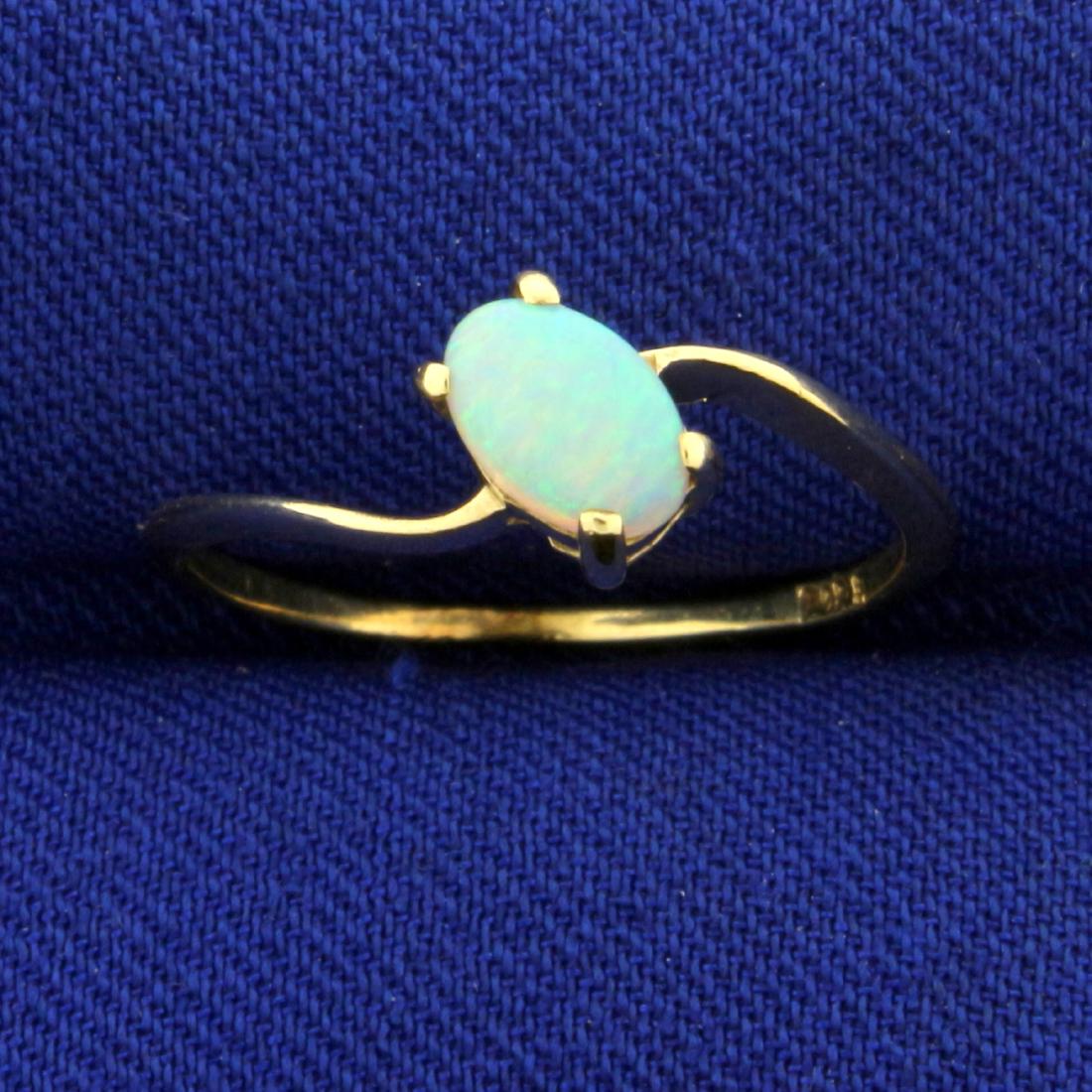 Solitaire Opal Ring in 14K Yellow Gold: In 14K Yellow Gold. Contains a 6x4mm high quality oval shaped natural Opal gemstone with excellent play of color, showing flashes of green, blue, and orange. Size 6. 1.1g