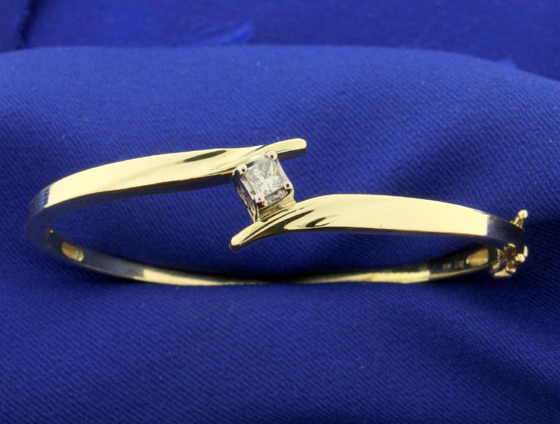 1/4 ct Diamond Bangle Bracelet: In 10k yellow gold. Contains a 1/4 ct princess cut high quality diamond, SI clarity/H color. With double safety clasp. 2 1/8 inch inside diameter. Opens/closes for easy putting on and taking off. 9.9g
