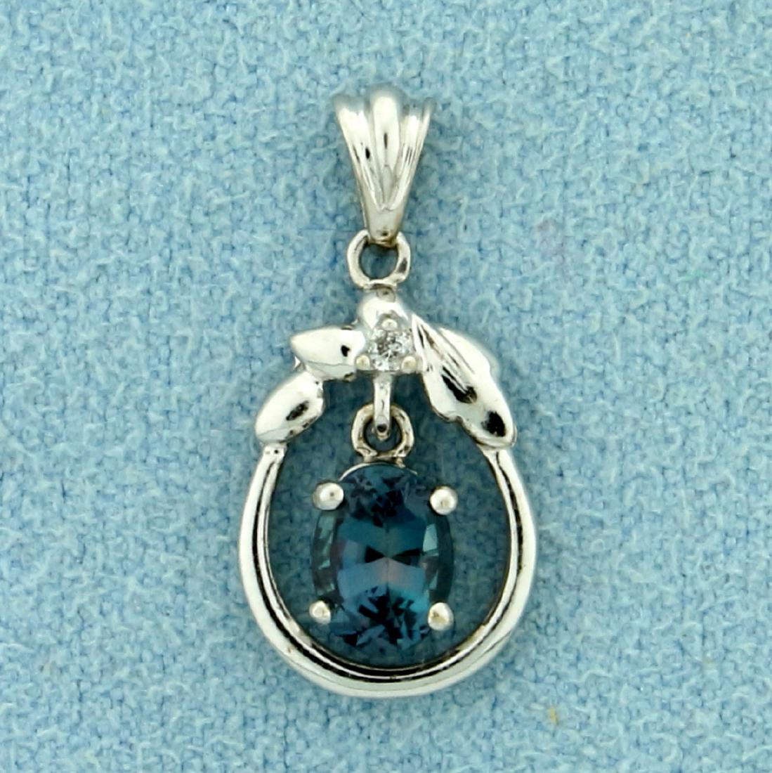 Diamond Pendant with Dangling Lab Alexandrite in 10K: In 10K White Gold. Contains a Lab 6x4mm Alexandrite gemstone that changes color from green to purple depending on light source. Also contains a high quality 1/2pt round Diamond. 3/4 inch long with bal