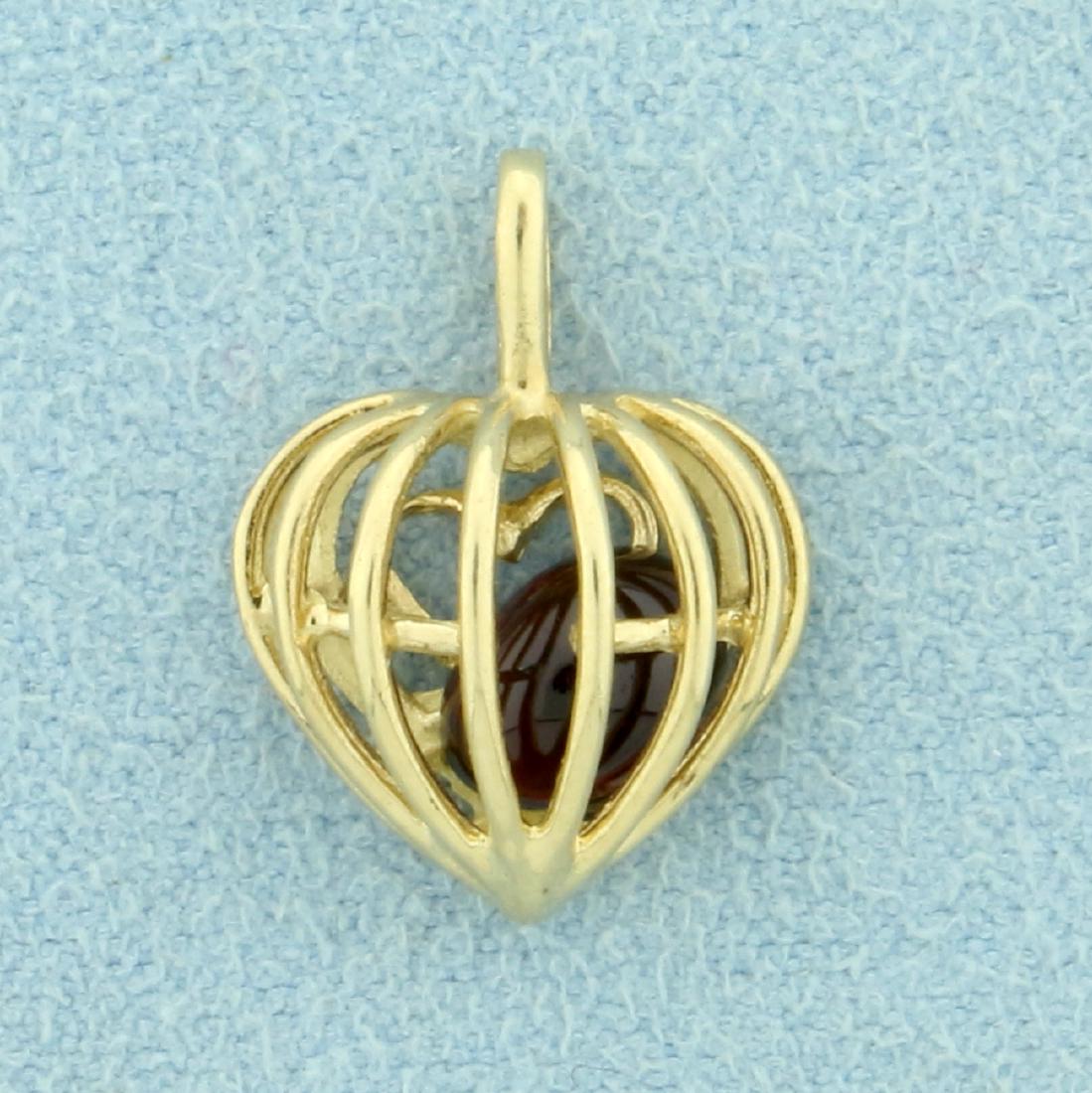 Heart Cage Pendant with Garnet Gemstone in 10K Yellow: In 10K Yellow Gold. Contains a natural high quality 7x5mm oval shaped Garnet gemstone that is free to move around in heart. 3/4 inch long with bale. 1.4g