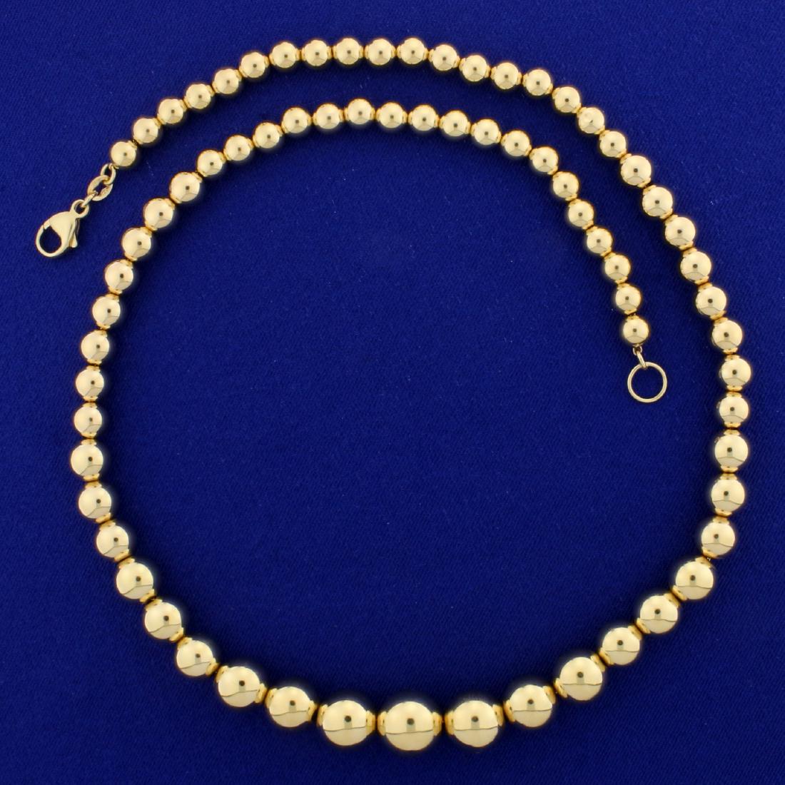 20 1/2 Inch Graduating Gold Ball Neck Chain in 14K: In 14K Yellow Gold. Graduating gold ball beads range from 6 to 12mm in diameter, with lobster clasp. 13.8g