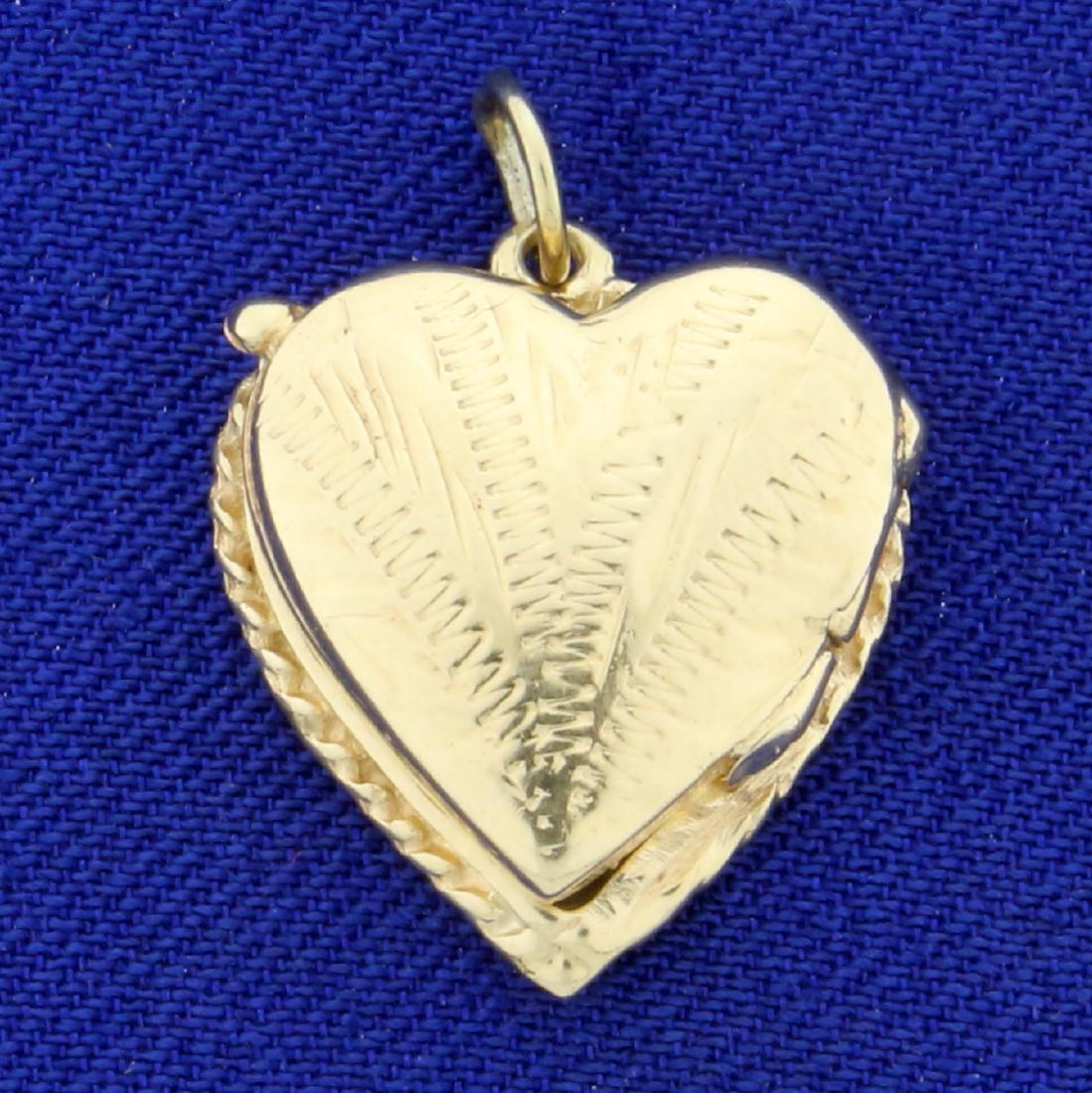 Antique Heart Locket Pendant or Charm in 14K Yellow: In 14K Yellow Gold. 5/8 inch wide, 7/8 inch long. Hinged design and hand engraved. 3.0g.