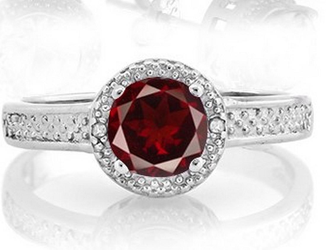 Garnet Halo Style Ring in Sterling Silver: Contains 1-6mm round cut Garnet gemstone with excellent clarity and Persian Red color, accented with .01ctw diamonds. Metal is fashioned to reflect light with a beautiful halo style design. Set in pla