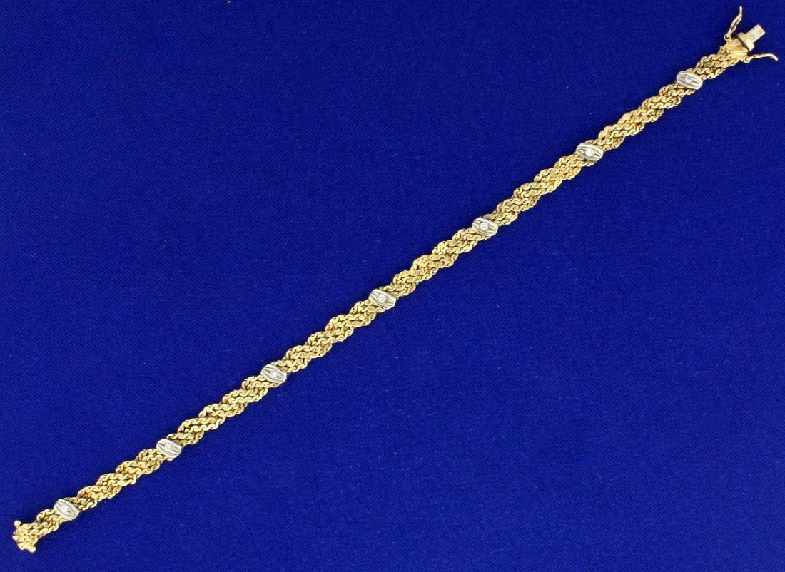 Italian Made Intricate Woven S Link Diamond Bracelet in: In 14k yellow and white gold, containing seven high quality .01ct diamonds, SI clarity/H color. 5mm wide, with safety clasp. 7 1/4 inches long. 10.5g.