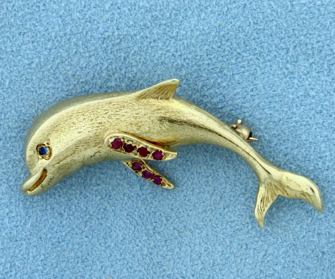 Sapphire and Ruby Dolphin Pin in 14K Yellow Gold: In 14K Yellow Gold. Contains seven high quality natural 1.5mm Ruby gemstones and a high quality natural 1.5mm Sapphire gemstone. 1 1/2" long. 4.9g