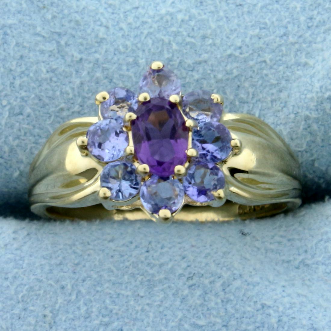 Amethyst and Tanzanite Flower Ring in 14K Yellow Gold: In 14K Yellow Gold. Contains a high quality natural 6 x 4mm oval Amethyst gemstone with vibrant purple color and excellent clarity. Also contains eight high quality natural 3mm Tanzanite gemstones wit