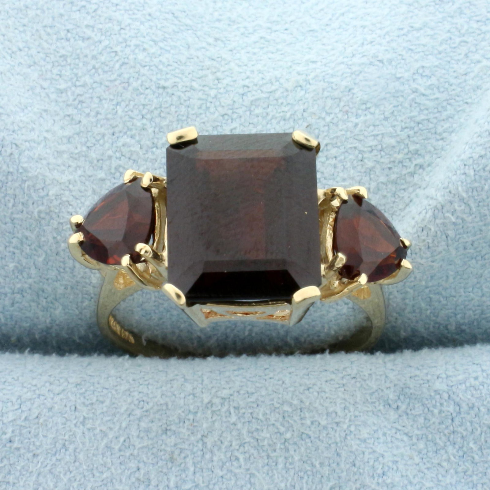 3-Stone Garnet Ring in 10K Yellow Gold: In 10K Yellow Gold. Contains one high quality natural 12 x 10mm and two 6mm trillion cut Garnet gemstones with beautiful deep red color and excellent clarity. Size 8 1/2. 4.6g.