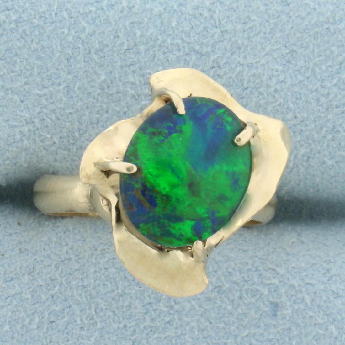 Black Opal Doublet Solitaire Ring in 14K Yellow Gold: In 14K Yellow Gold. Contains one high quality natural 12x10mm oval Black Opal doublet gemstone with intense blue and green color. Size 7 1/4. 4.9g