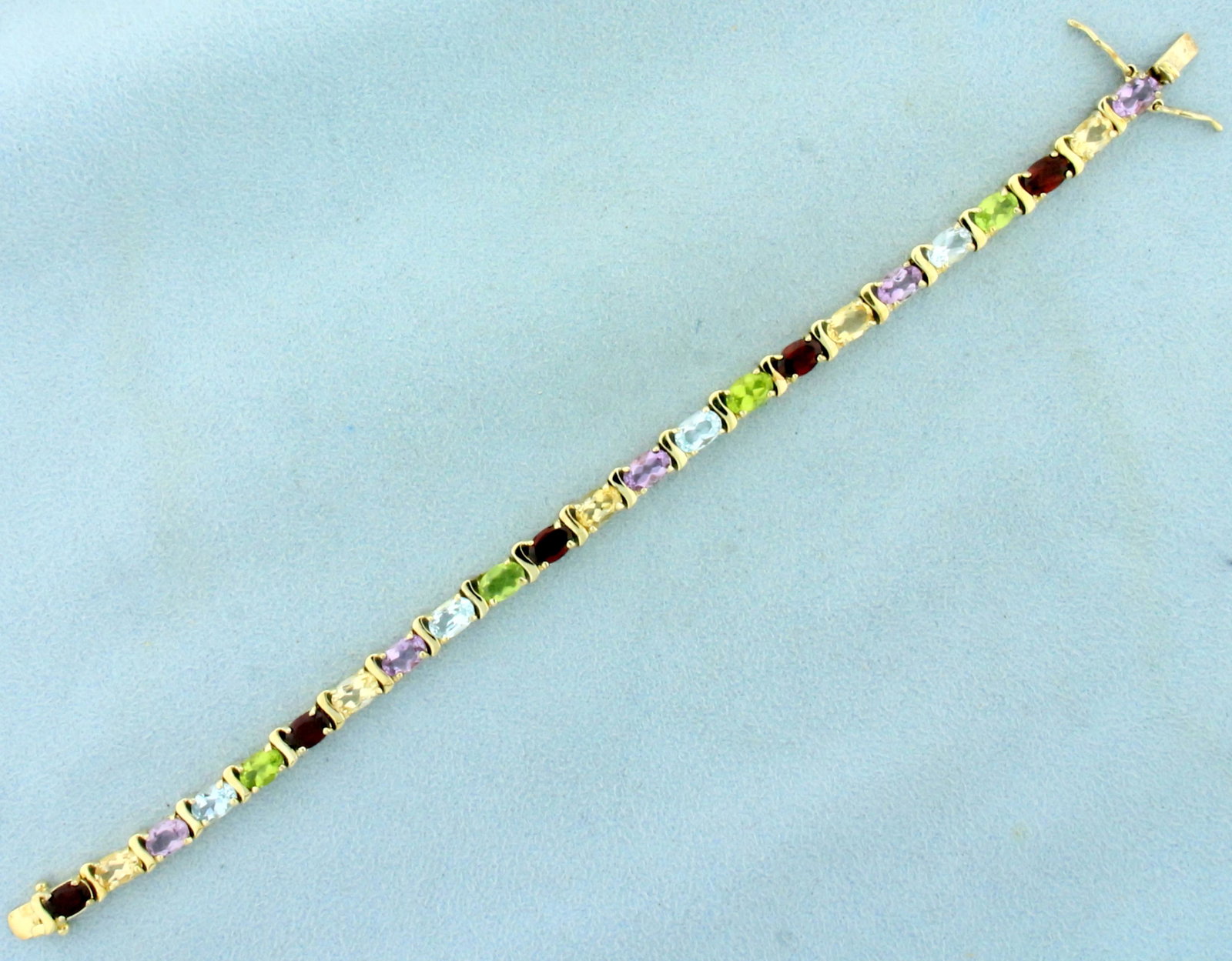 12ct TW Multi Gemstone Line Bracelet in Gold Plated: In gold plated sterling silver. Contains five 6x4mm oval cut Amethyst, Citrine, and Garnet gemstones. Also contains four 6x4mm Peridot and Sky Blue Topaz gemstones. All with vibrant color and excellen