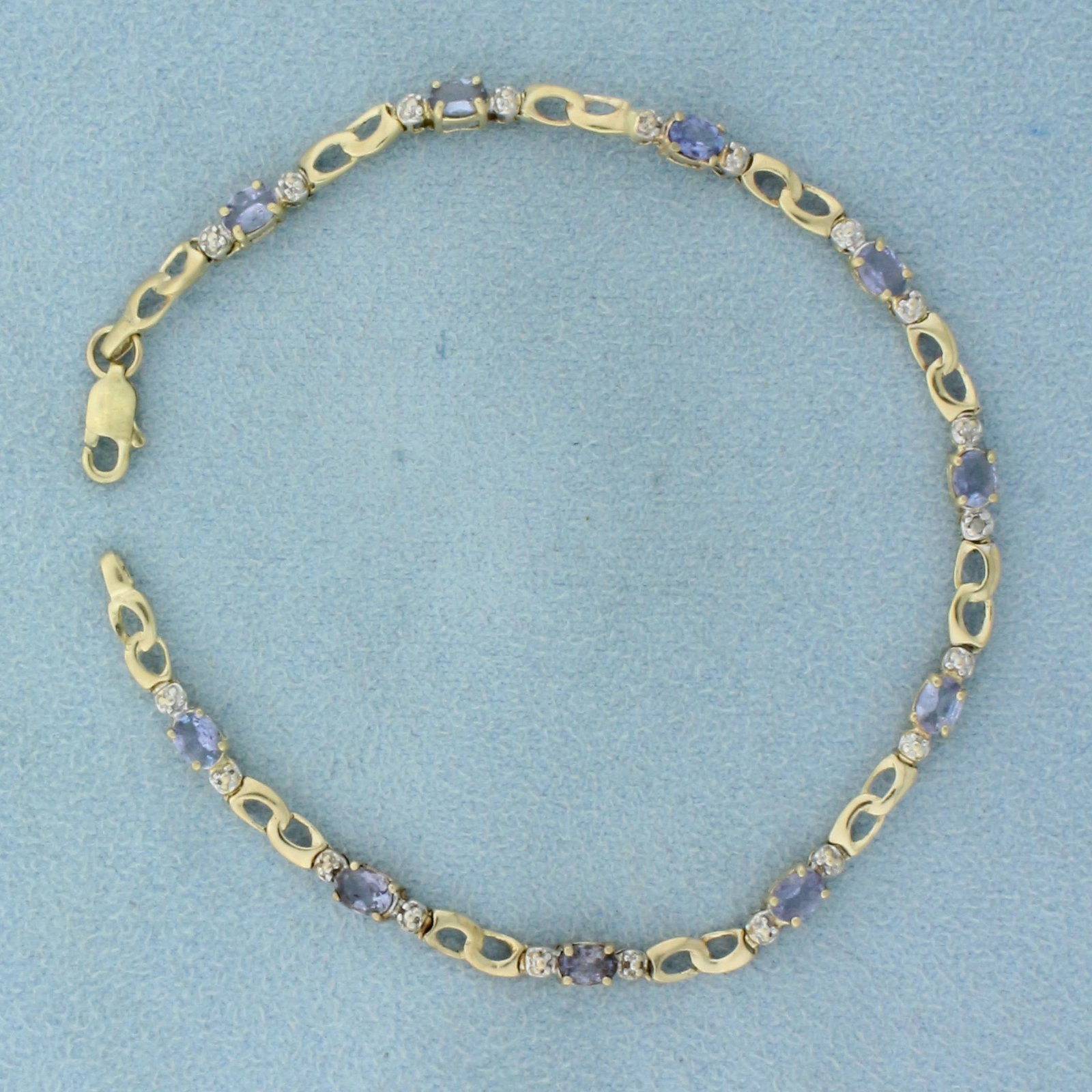Tanzanite and Diamond Tennis Bracelet in 10K Yellow: In 10K Yellow Gold. Contains ten high quality natural 4x3mm oval cut Tanzanite gemstones with excellent clarity. Also contains two high quality 1/2pt round cut Diamonds. 7 1/4 inches long. 3.6g
