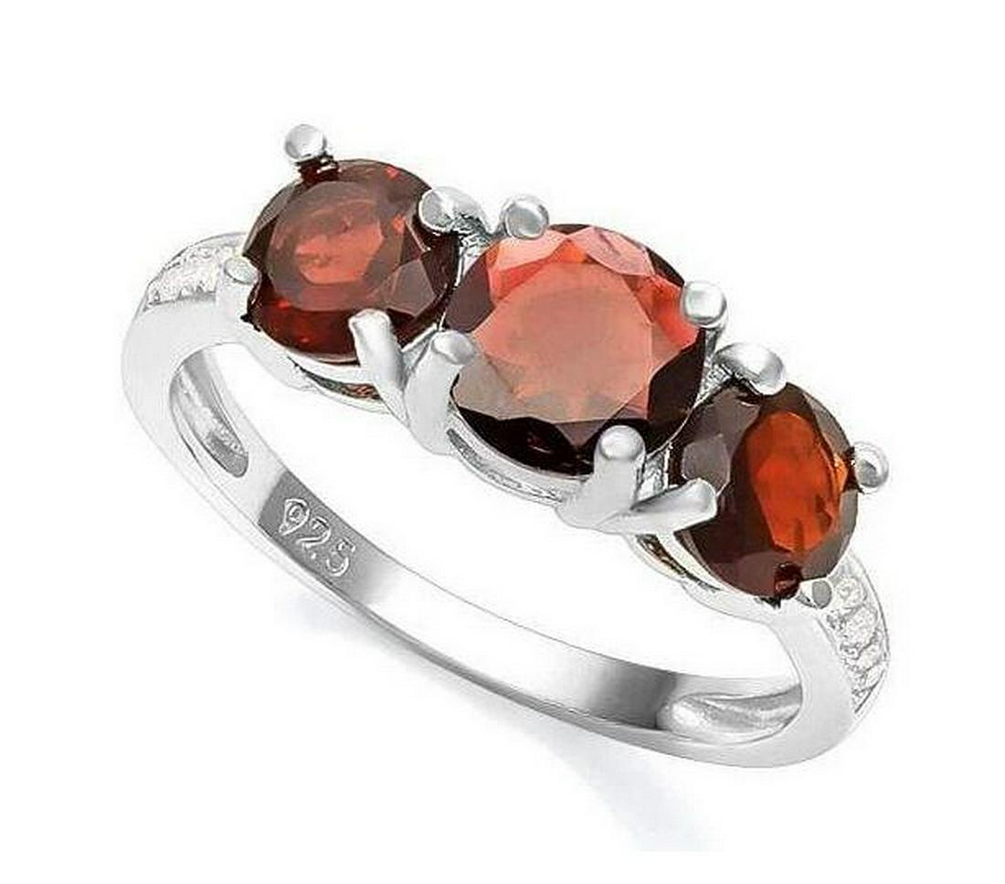 Classic Garnet 3-Stone Ring in Sterling Silver: Round cut 1ct garnet gemstone ring, accented with 1.2ctw round cut garnet gems and white sapphire in the band. Size 7. Set in platinum over sterling silver, 2.4g.