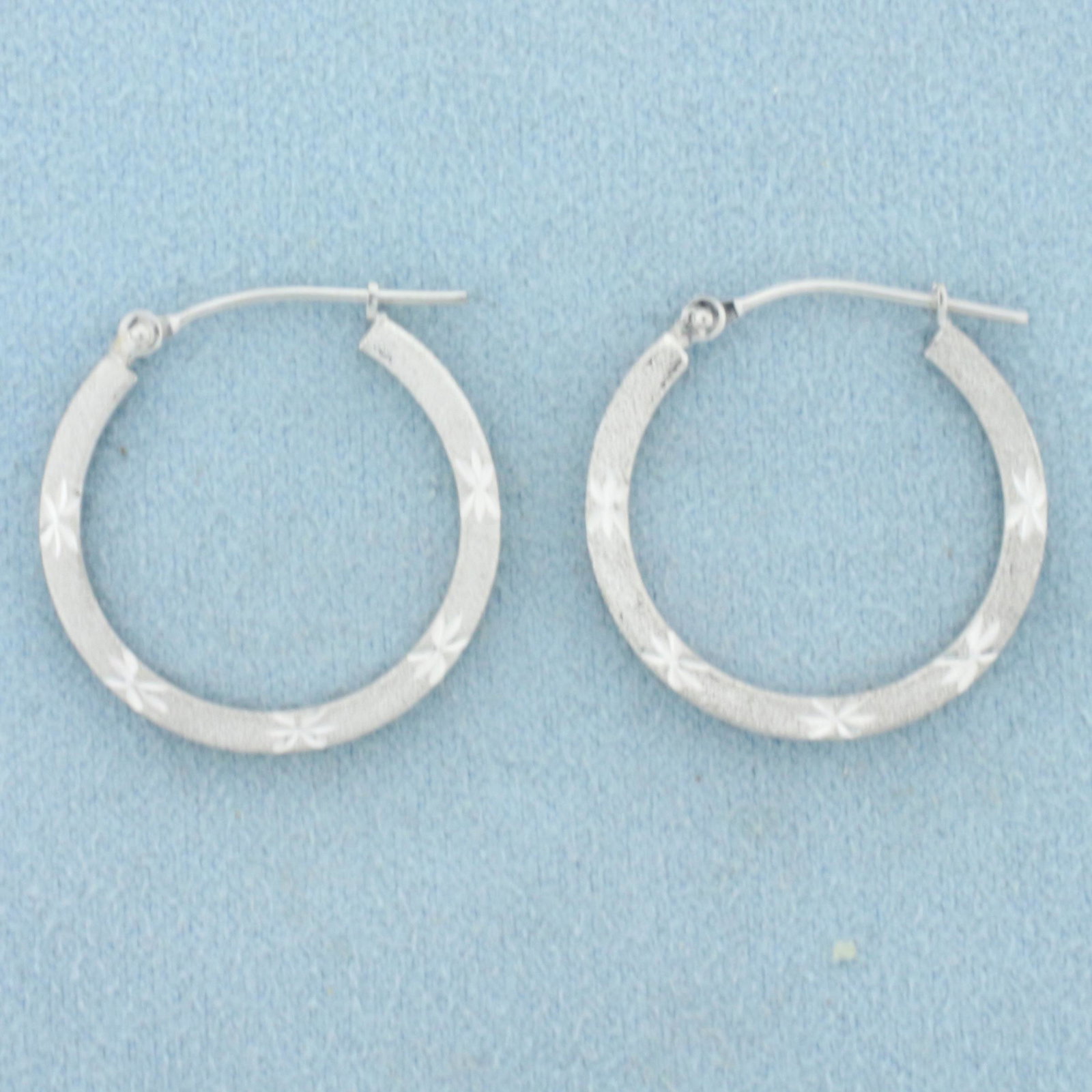 Diamond Cut Sandblast Finish Hoop Earrings in 14K White: In 14K White Gold. Star pattern is diamond cut for extra sparkle, unique sandblast finish. 7/8 inch long. 1.8g.