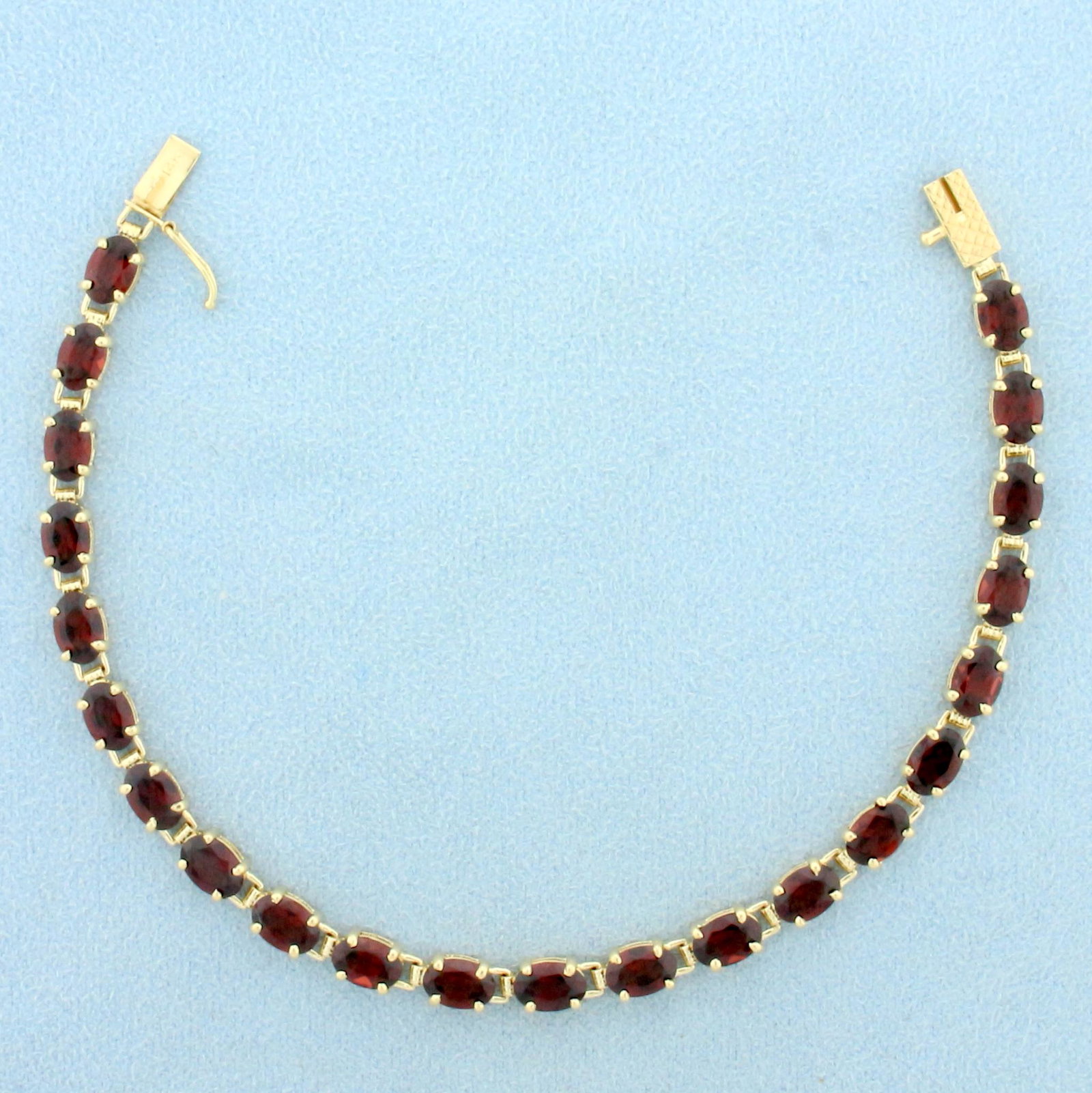 12ct TW Garnet Line Tennis Bracelet in 14K Yellow Gold: In 14K Yellow Gold. Contains twenty-two high quality natural 6.x4mm oval cut Garnet gemstones with vibrant color and excellent clarity. 7 1/8 inches long. 4.2mm wide. Safety clasp. 7.5g