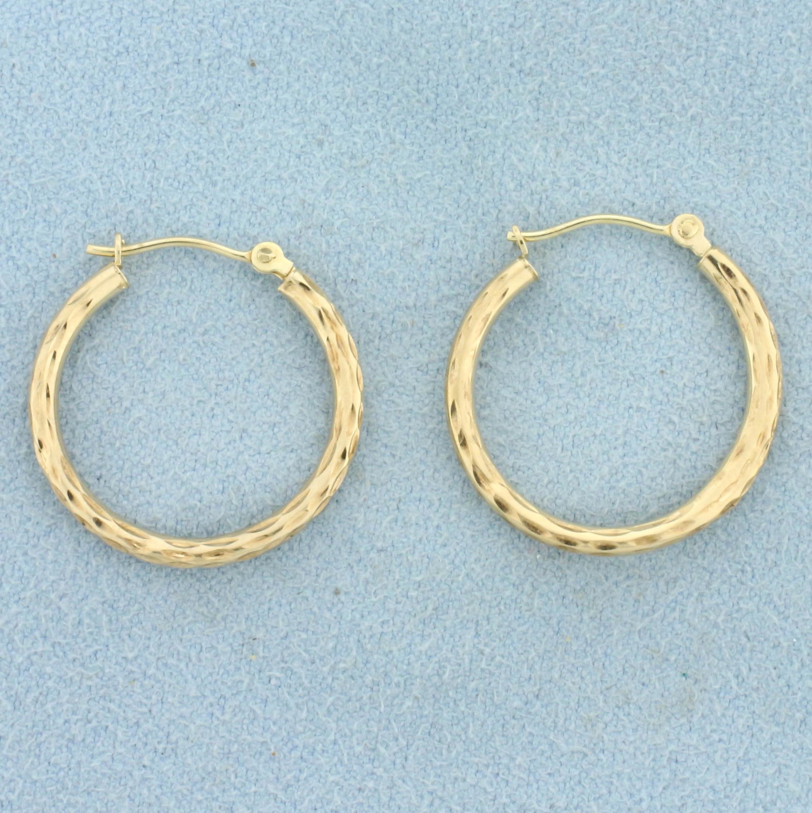 Hoop Earrings Dimple Design in 10k Yellow Gold: In 10k yellow gold. 7/8 inches in diameter, 2.0 mm thick. .7g.