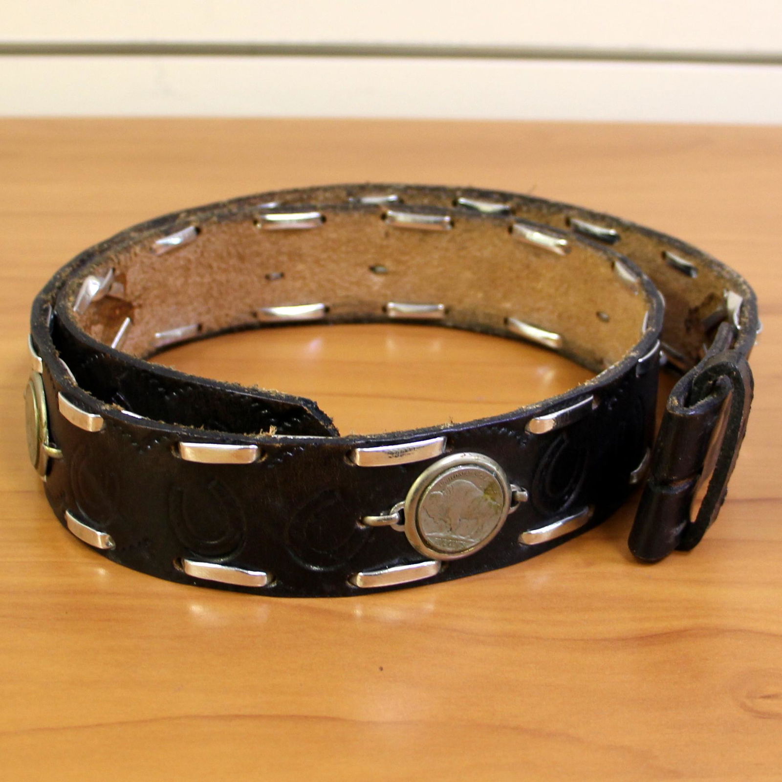Vintage Leather Tooled Belt with Buffalo Nickel: 40 inches long, 1.5" wide. Embossed with horseshoe design. Embellished with 6 buffalo nickels. Snap design on end to hold buckle (not included.)