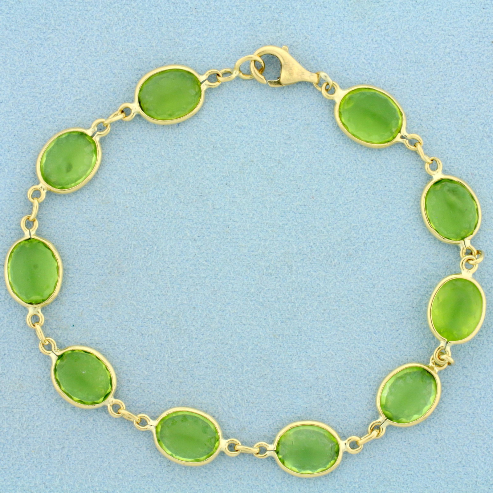 Vintage Peridot Bracelet in 18K Yellow Gold: In 18K Yellow Gold. Contains ten high quality natural 10 x 7.5mm oval cut Peridot gemstones with bright green color. Stones do have some abrasion on them, indicative of age. 8 inches long, 8.8mm wide.