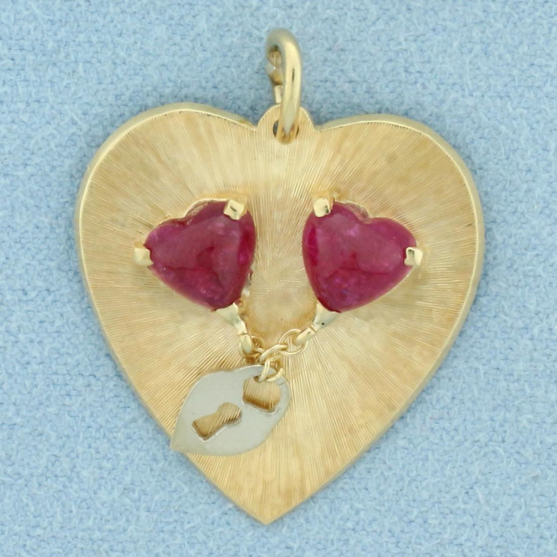 Heart Ruby Padlock Motion Pendant or Charm in 14k Yellow Gold: In 14k yellow gold. Contains 2 heart cabochon shaped high quality natural Ruby Gemstones, 6mm by 6mm each, with intense ruby red color. Etched finish on medallion for added reflection, movable dangle 