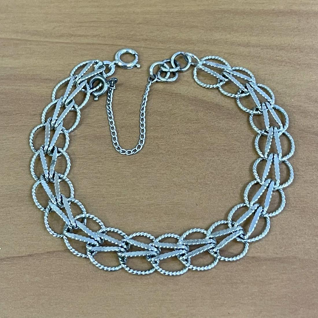 Charm Bracelet in Sterling Silver: In sterling silver. 7.5 inches long, 10.5mm wide. Safety chain. 9.2g