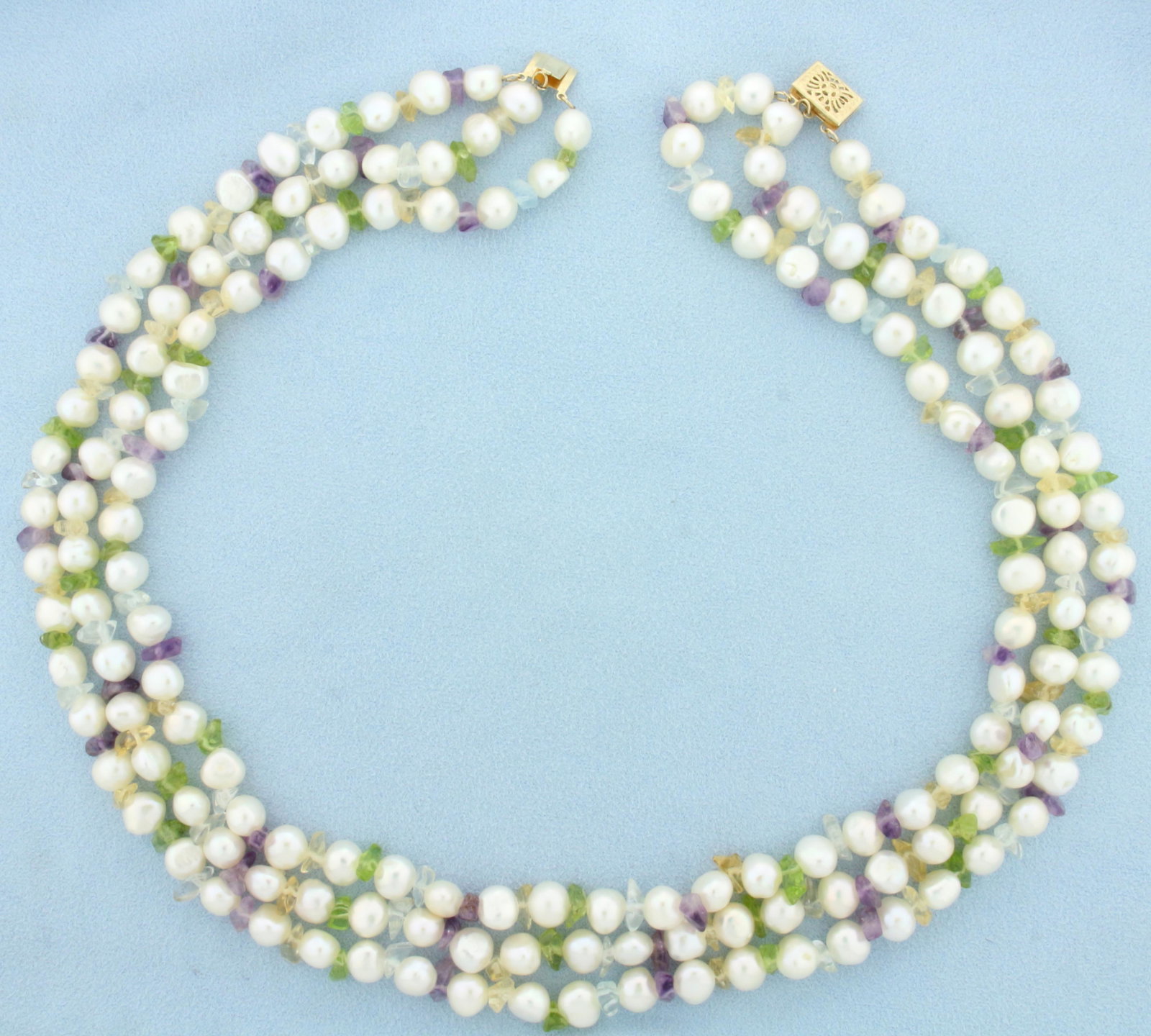 Triple Strand Pearl and Gemstone Necklace in 14K Yellow Gold: 14K Yellow Gold clasp. Approximately 18 inches long with slide clasp. 6.5-7.5mm baroque Pearls are alternated with polished gemstone beads including Amethyst, Peridot, Citrine, and Topaz. 90.5g.