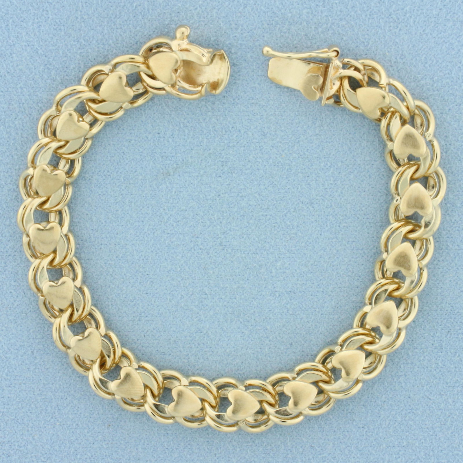 Heart Link Charm Bracelet in 14k Yellow Gold: In 14k yellow gold. Measures 7 inches long, 9mm wide. Slide clasp with safety latch. 25.5g.