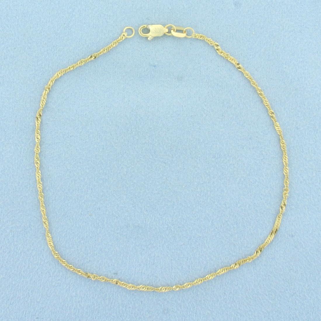 Twisting Curb Link Anklet in 14k Yellow Gold: In 14k yellow gold. 9 inches long, 1.5mm wide. Lobster clasp. 1.2g.