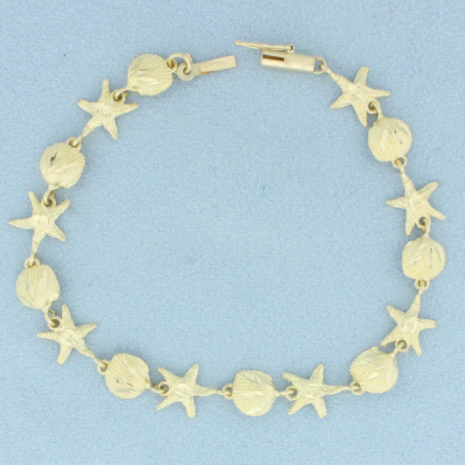 Seashell Starfish Bracelet in 14K Yellow Gold: In 14k yellow gold. 7 1/2 inches long, 9mm wide. Safety clasp. 6.7g.