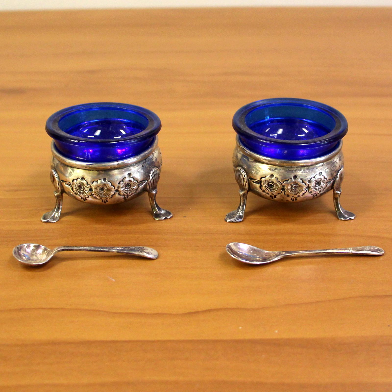 Vintage Baldwin and Miller Pair of Sterling Silver Footed Salt Cellars: .925 sterling silver. Numbered "43", hand chased, includes 2 cobalt blue glass inserts, includes 2 silverplated salt spoons, 167.6g (solid sterling + glass inserts), 80.0g (solid sterling).