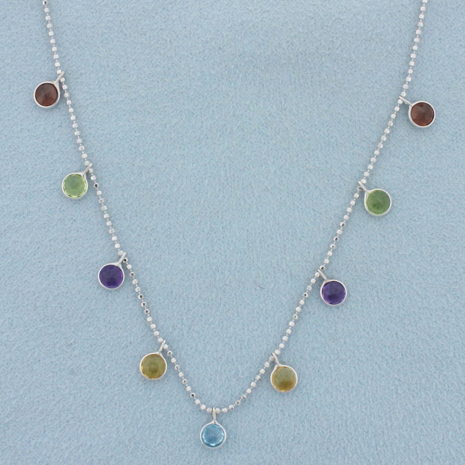 17 Inch Dangle Gemstone Station Necklace in 14k White Gold: In 14k white gold. Contains assorted high quality 4mm gemstones: 2 garnet, 2 peridot, 2 citrine, and 1 blue topaz. All with bright color and excellent clarity. Chain is beveled ball link, 17 inches lo