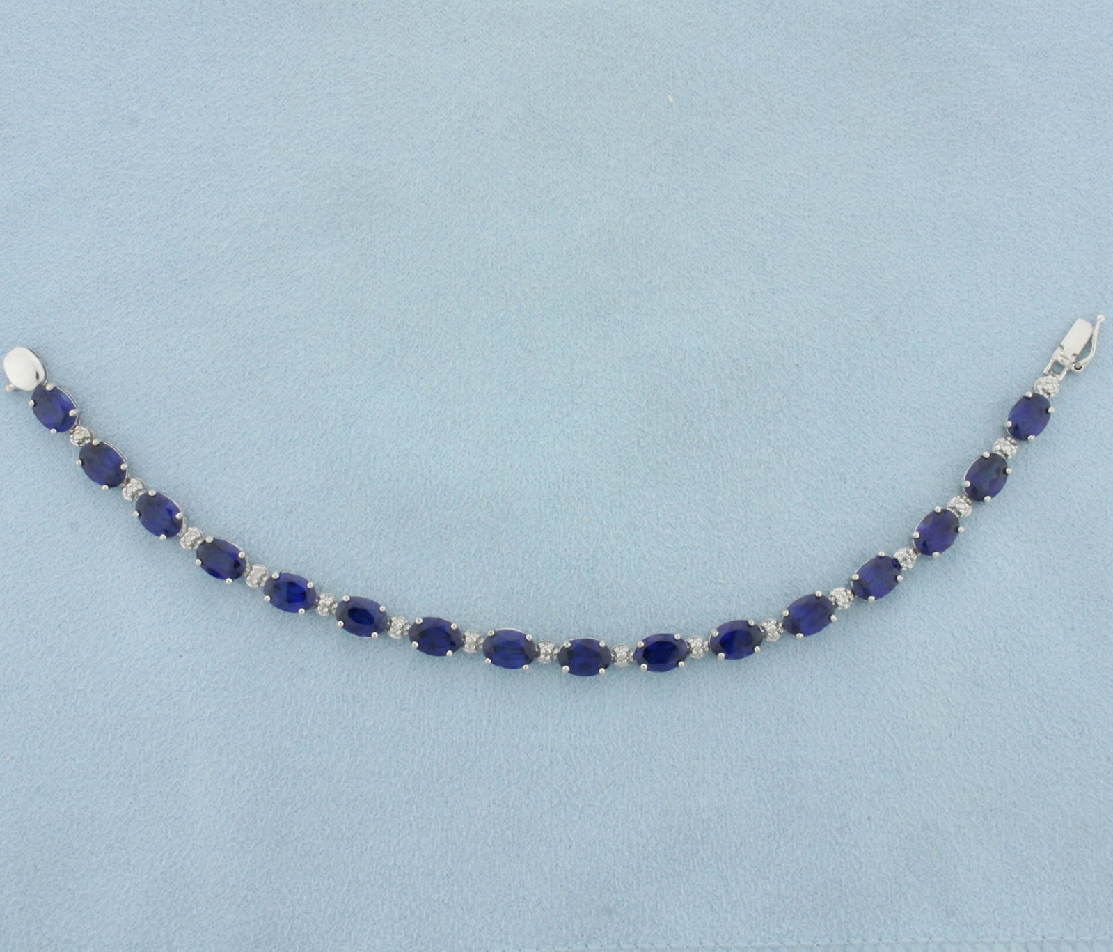 Lab Sapphire and Diamond Tennis Bracelet in 10k White Gold: In 10k white gold. Contains 16 high quality 1ct oval cut lab sapphires with intense blue color and excellent clarity. Accented with seven 1/2pt diamonds. Slide in button clasp with safety latch. 7.9g.