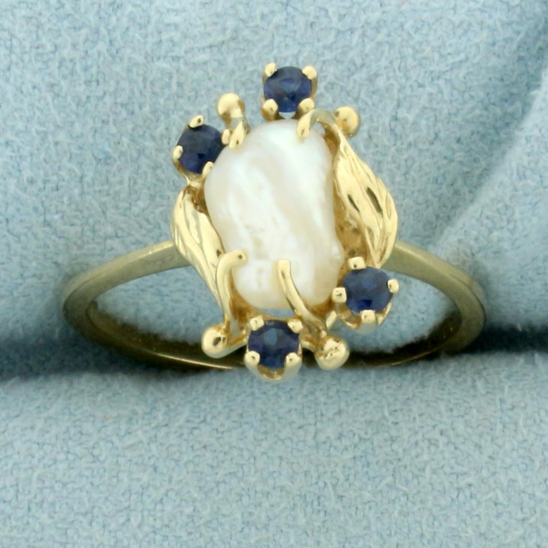 Baroque Pearl and Sapphire Ring in 14k Yellow Gold: In 14k yellow gold. Contains one baroque freshwater pearl, 10mm x 6.5mm, with high luster. Accented by four sapphires, 2.2mm each, 1/4ctw, with intense color and excellent clarity. Size: 8. 2.9g.