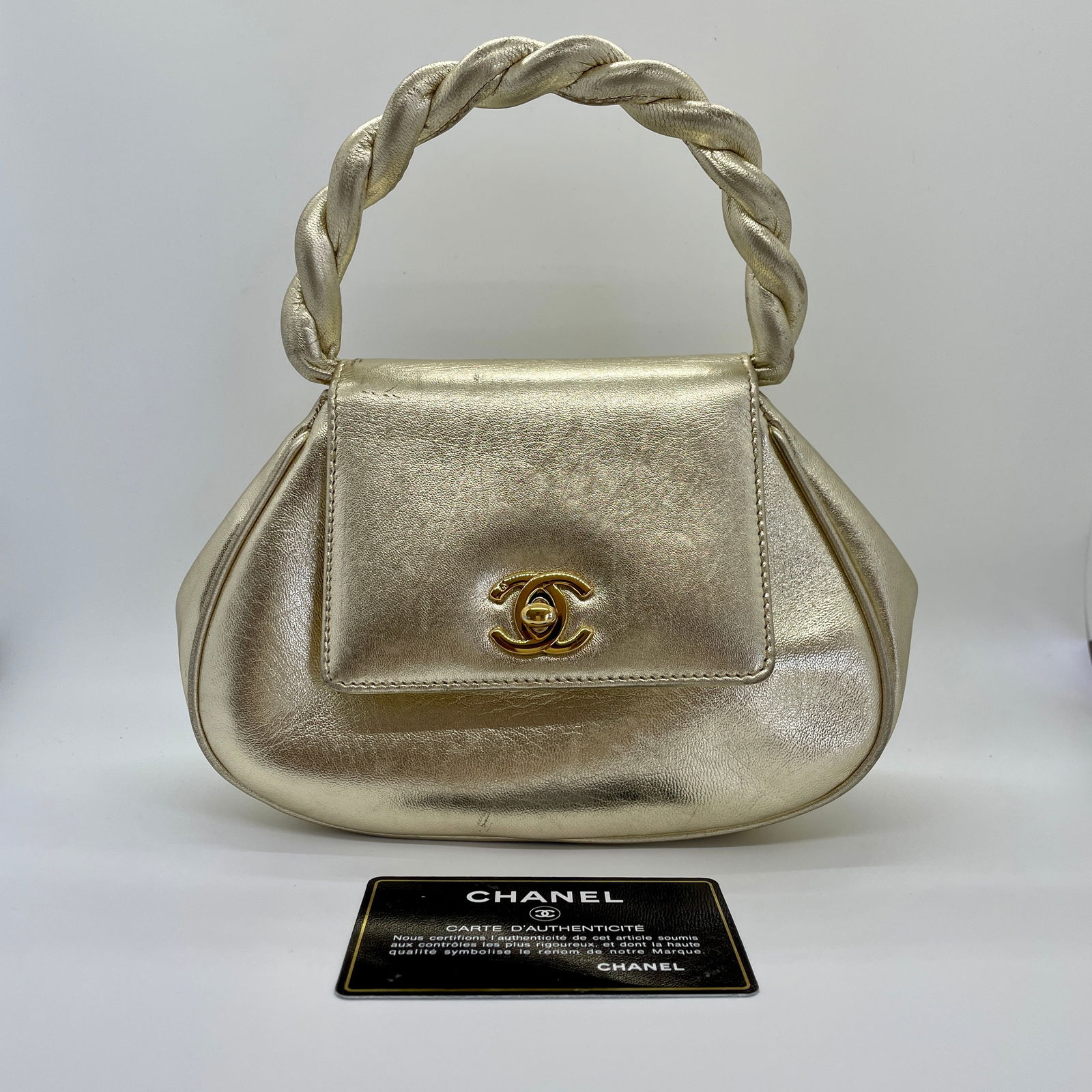 Chanel Metallic Gold Twisted Top Handle Evening Bag: Chanel metallic gold twisted top handle evening bag with 24k gold plated hardware. Iconic CC turnlock. Metallic gold lined interior with zip pocket and CC pull tab. Hologram sticker inside bag with ma