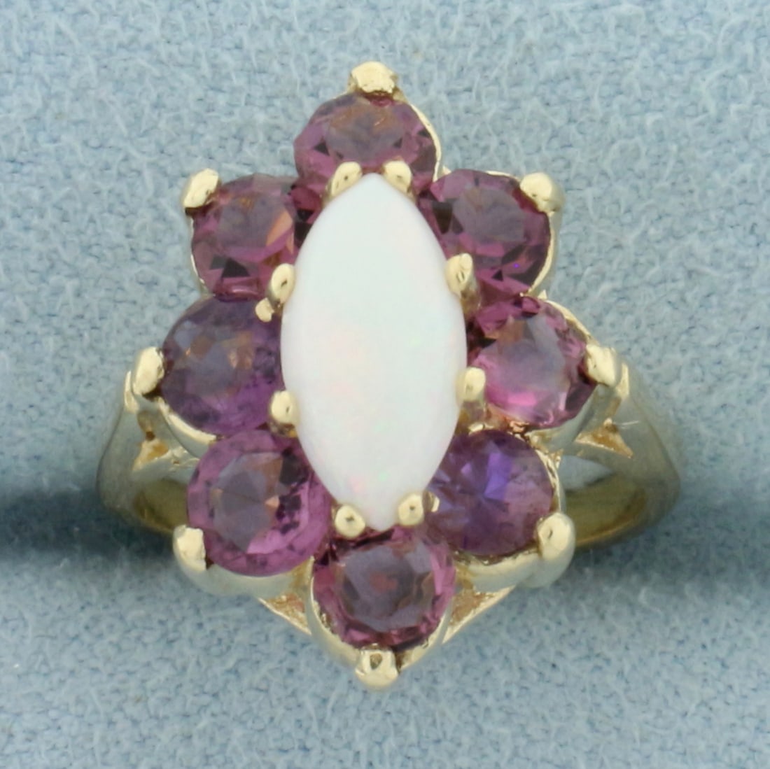 Opal and Tourmaline Halo Flower Ring in 14k Yellow Gold: In 14k yellow gold. Contains one high quality natural marquise shaped opal gemstone, 10mmx5mm, with excellent play of color and flashes of pink, orange, green and yellow. Accented by eight high qualit