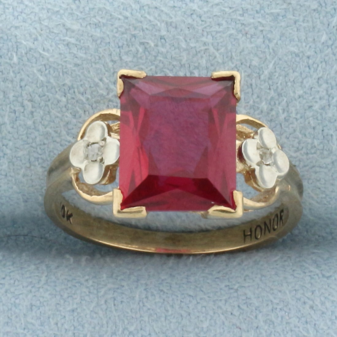 Vintage Lab Ruby and Diamond Flower Ring in 10k Yellow Gold: In 10k yellow gold. Contains one high quality 10mm by 8mm lab Ruby gemstone, approximately 3ct, with excellent color and clarity. Also contains two .01ct old table cut diamonds. Size 5.5. 2.9g.