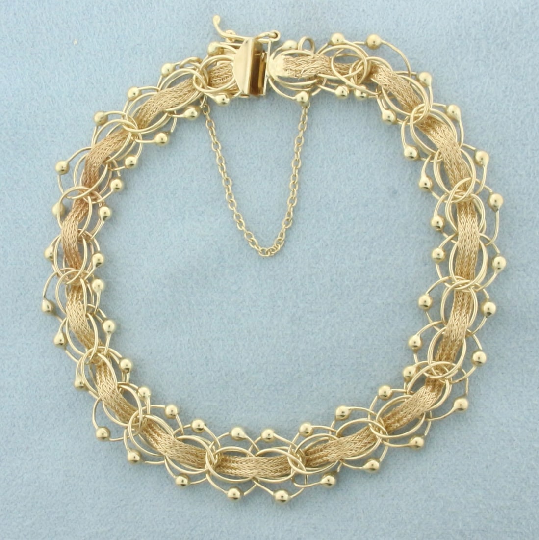 Beaded Woven Design Charm Bracelet in 14k Yellow Gold: In 14k yellow gold. 7 3/8 inches long x 3/8 inches wide. Concealed slide clasp with safety latch and safety chain. 11.7g.