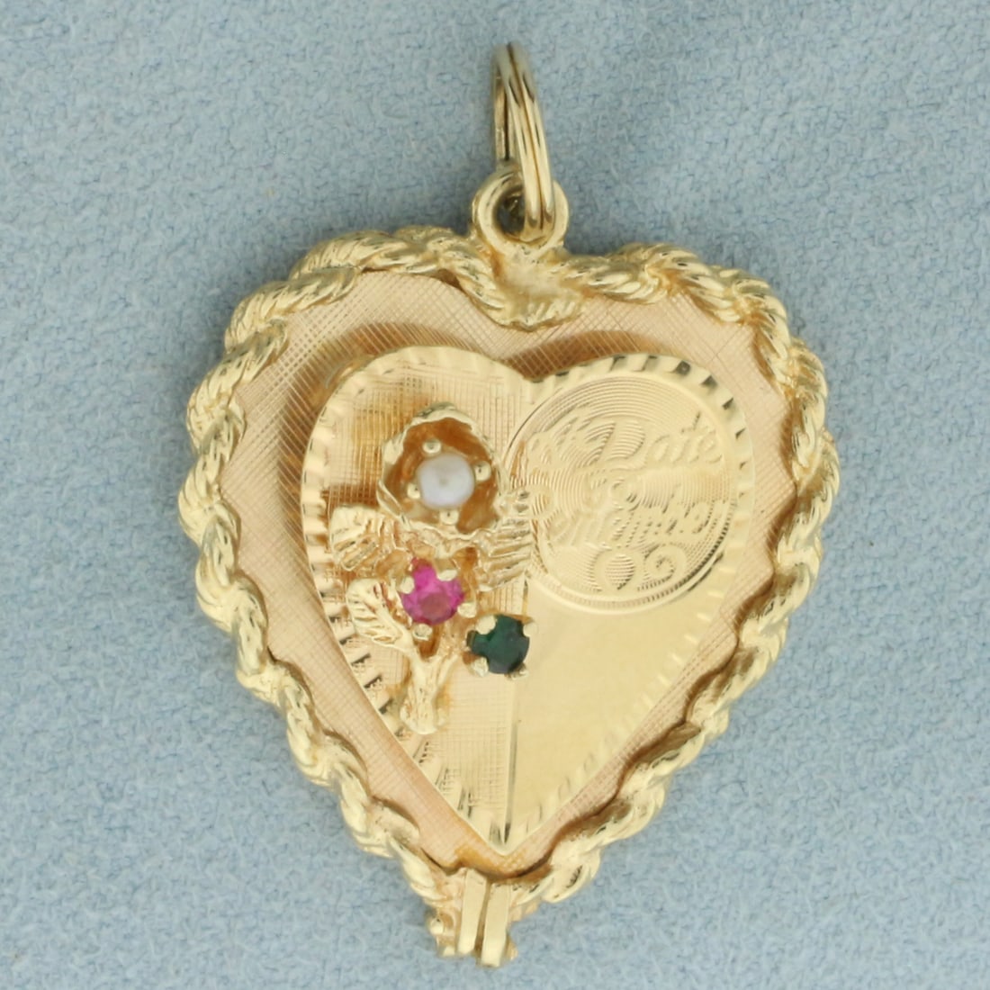 A Date To Remember 3D Heart pendant in 14k Yellow Gold: In 14k yellow gold. Contains one high quality 3mm Pink Sapphire and Emerald gemstones with intense color and excellent clarity. Also contains one seed pearl. 1 1/2 inches long and 1 1/8 inches wide. C