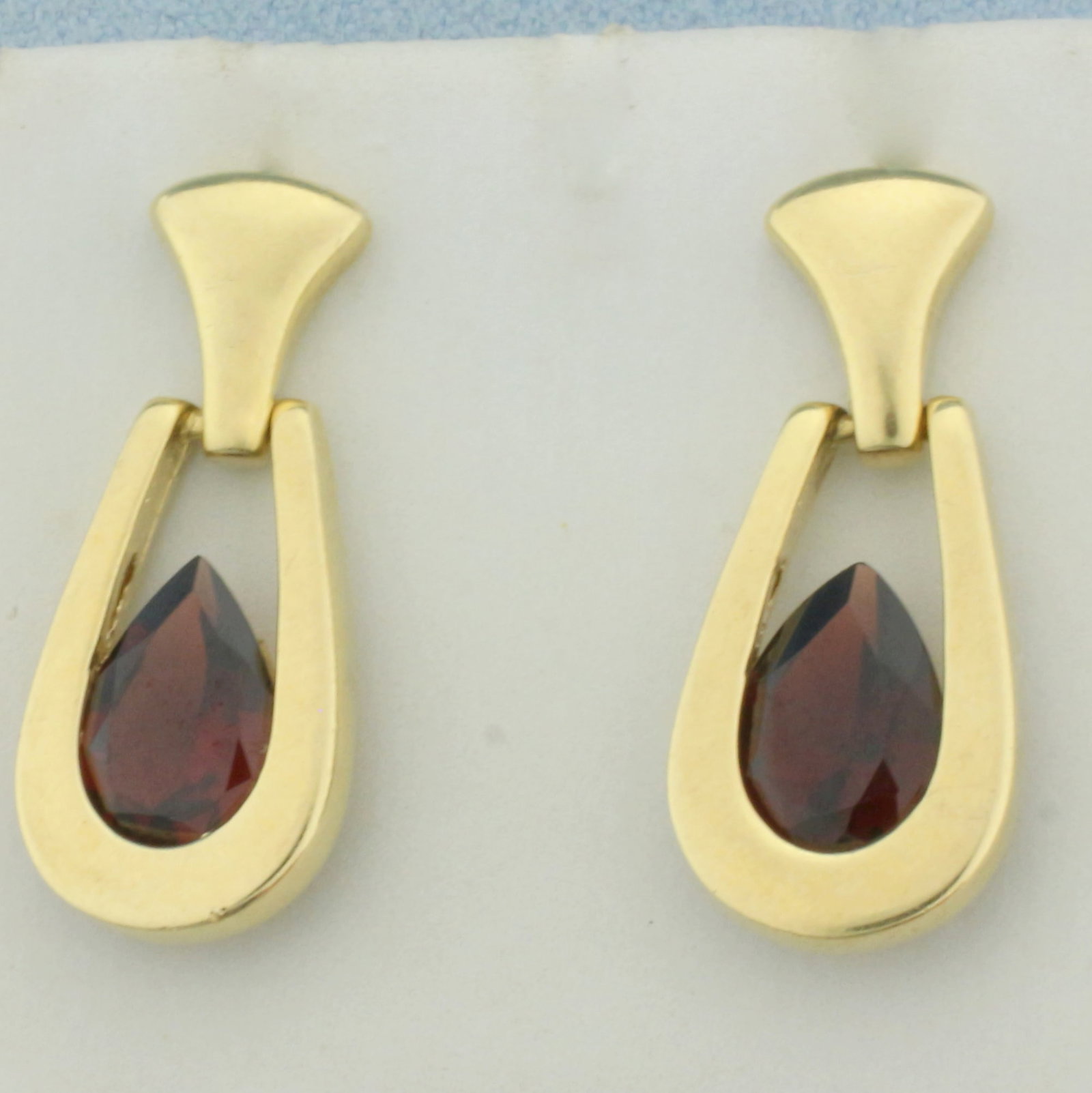 Garnet Dangle Earrings in 14k Yellow Gold: In 14k yellow gold. Contains two high quality 9mmx7mm natural pear cut Garnet gemstones with deep color and excellent clarity. Measures 1 inch long, 1/2 inch wide. Friction backs. 6.4g.