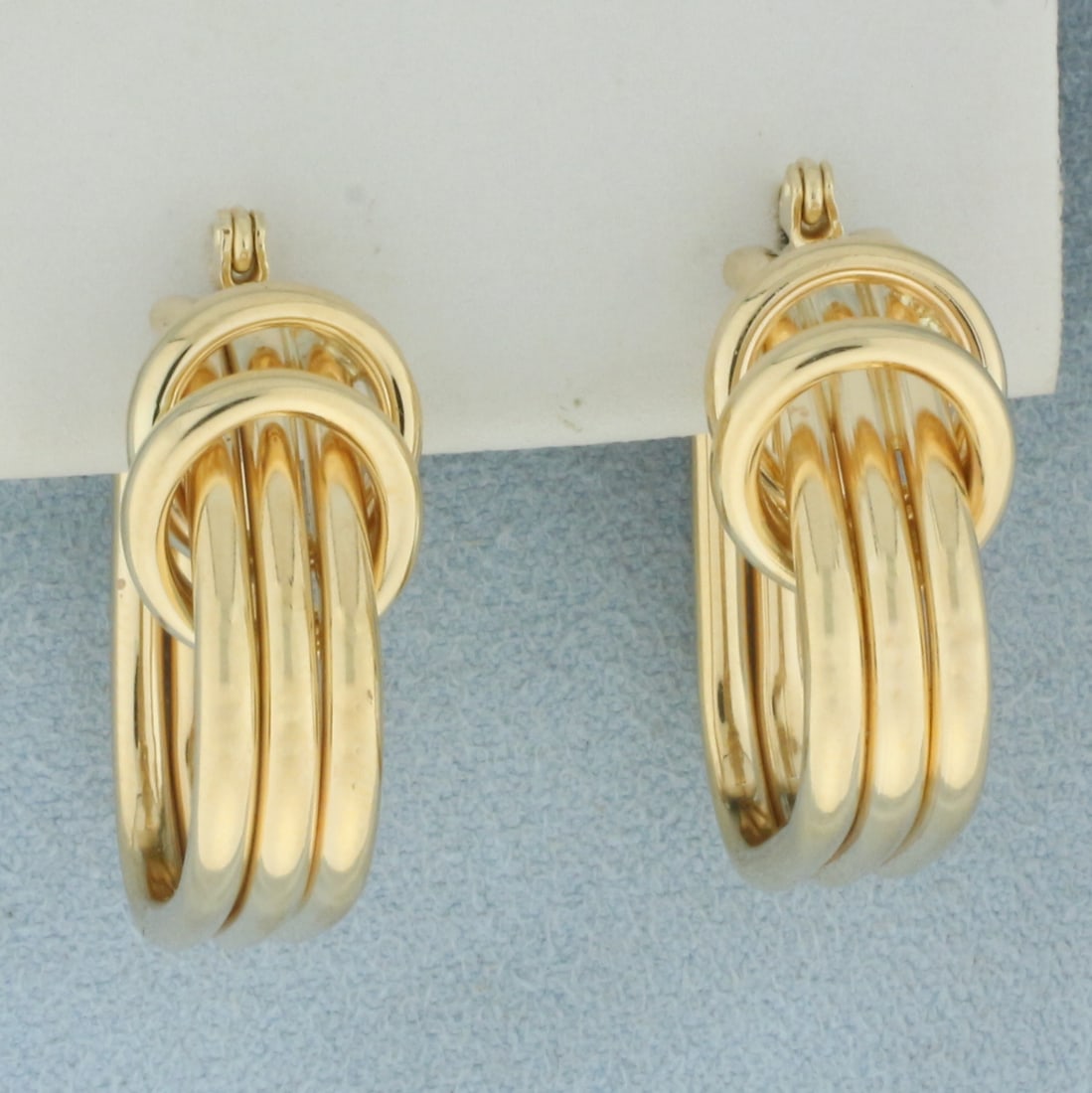 Triple Rings Hoop Earrings in 14k Yellow Gold: In 14k yellow gold. 1 inch long, 7/8 inches wide. Very minor indentation on back side of one earring. Lever back. 5.0g.