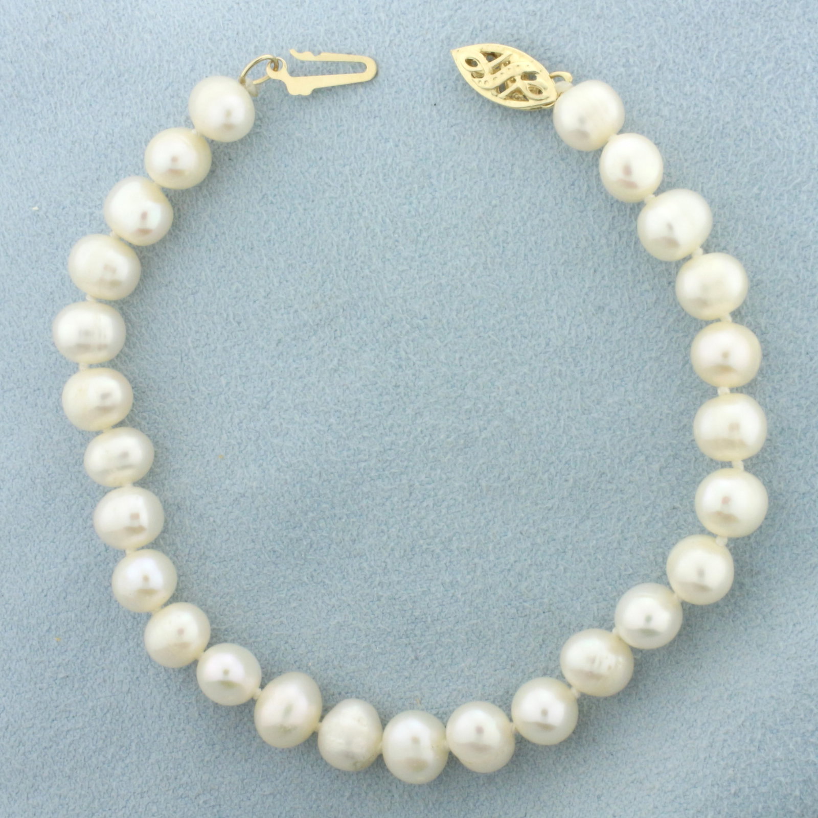 Cultured Pearl Bracelet in 14k Yellow Gold: 14k yellow gold clasp. Contains high quality 7mm cultured pearls with high luster. Filigree locking clasp. Hand knotted.