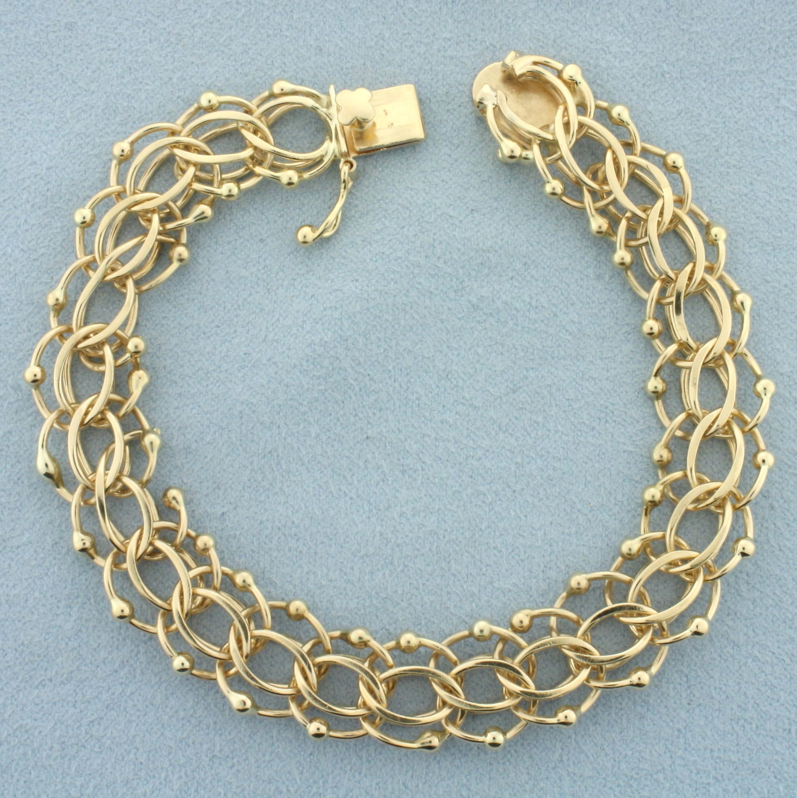 Multi Loop Charm Bracelet in 14k Yellow Gold: In 14k yellow gold. 7 1/4 inches long x 12mm wide. Concealed clasp with safety latch. 21.7g.