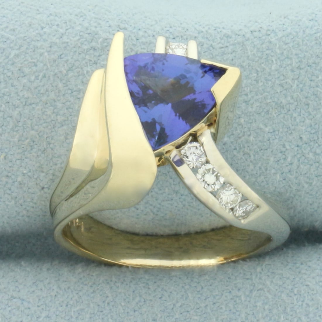 Tanzanite and Diamond Designer Ring in 14k Yellow and White Gold: In 14k yellow and white gold. Contains one high quality natural AAA quality 9mm trillion cut tanzanite with intense sapphire like color and excellent clarity. Also contains six high quality diamonds, 