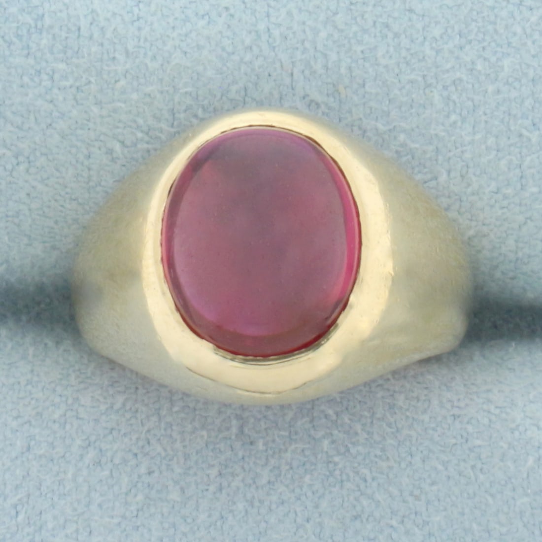 Lab Ruby Ring in 10k Yellow Gold: In 10k yellow gold. Contains one oval cabochon lab ruby gemstone, 12mm x 10mm, with vibrant ruby red color and excellent clarity. Size 6.5