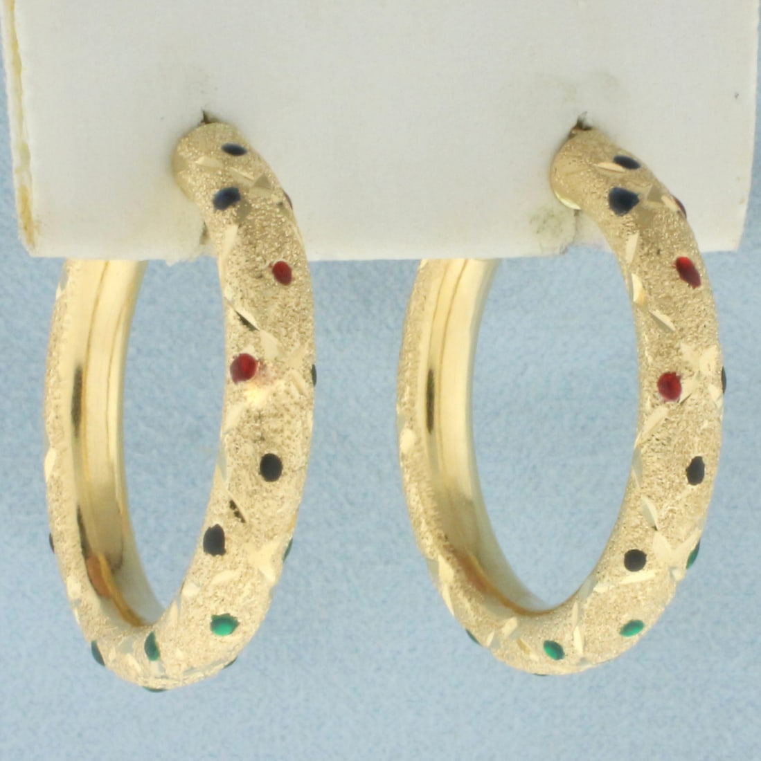 Enamel Sparkle Finish Hoop Earrings in 14k Yellow Gold: In 14k yellow gold. 1 1/8 inch diameter, 4.25mm wide tubes. Accented with green, yellow, blue, and black enamel to mimic precious gemstones. Sparkle finish. Lever backs. 4.5g.