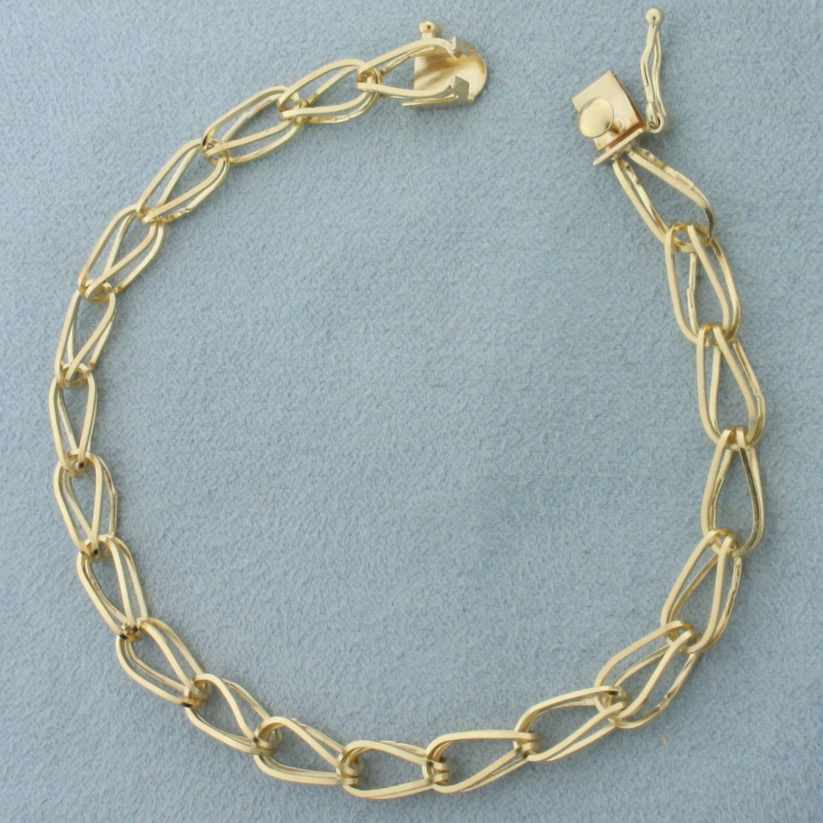 Double Tapered Loop Link Charm Bracelet in 14k Yellow Gold: In 14k yellow gold. Concealed slide clasp with safety latch. 7.5 inches long, 5mm wide. 5.7g.