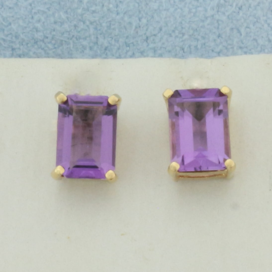 Emerald Cut Amethyst Stud Earrings in 14k Yellow Gold: In 14k yellow gold. Contains two high quality 5mm by 7mm emerald cut Amethyst Gemstones, 2ct TW, with vibrant color and excellent clarity. Basket 4-prong settings. Friction backs. 1.3g.