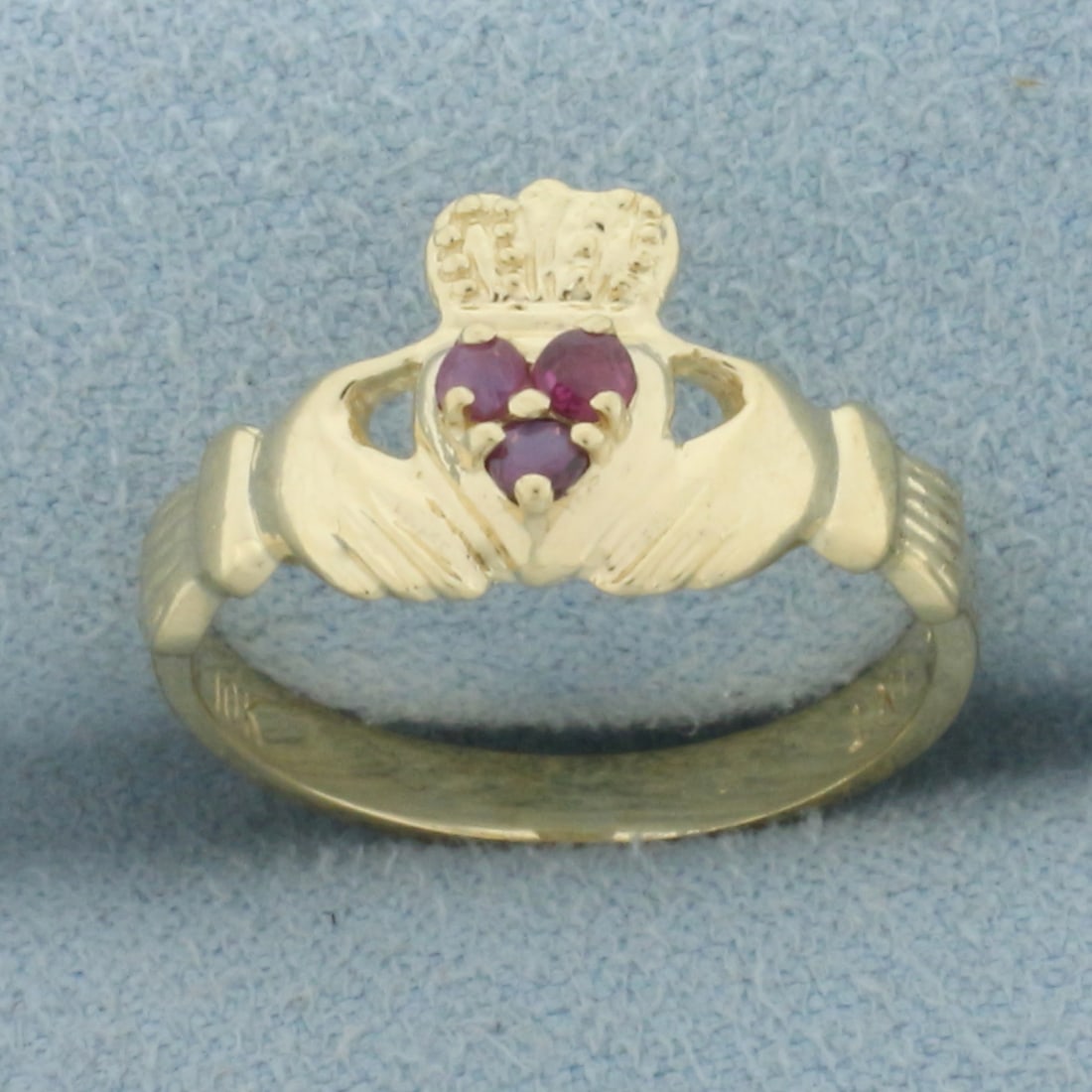 Ruby Claddagh Ring in 10k Yellow Gold: In 10k yellow gold. Contains three high quality natural 2mm Ruby gemstones with intense color and excellent clarity. 10mm wide at center of ring. Size: 5. 1.9g.